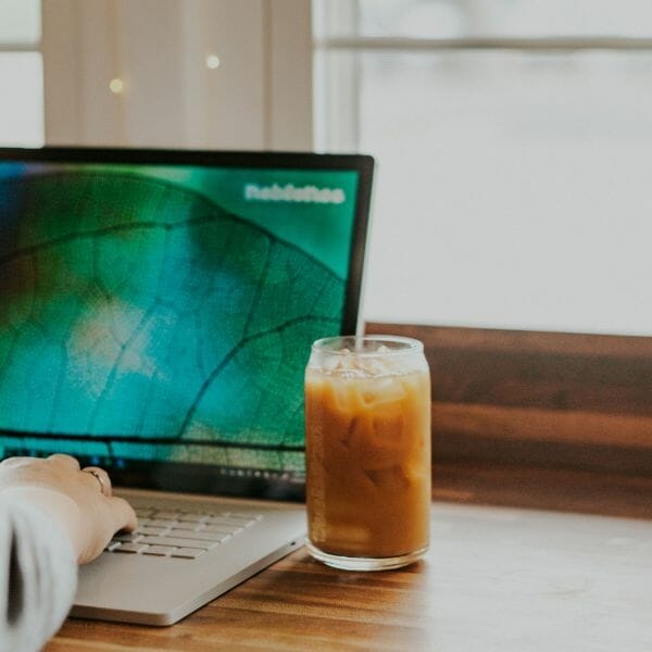 A laptop sits on a desk with iced coffee as Trebletree co-founder prepares to work on a franchise website. 